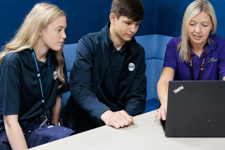 Photo of three members of staff sat in front of a laptop