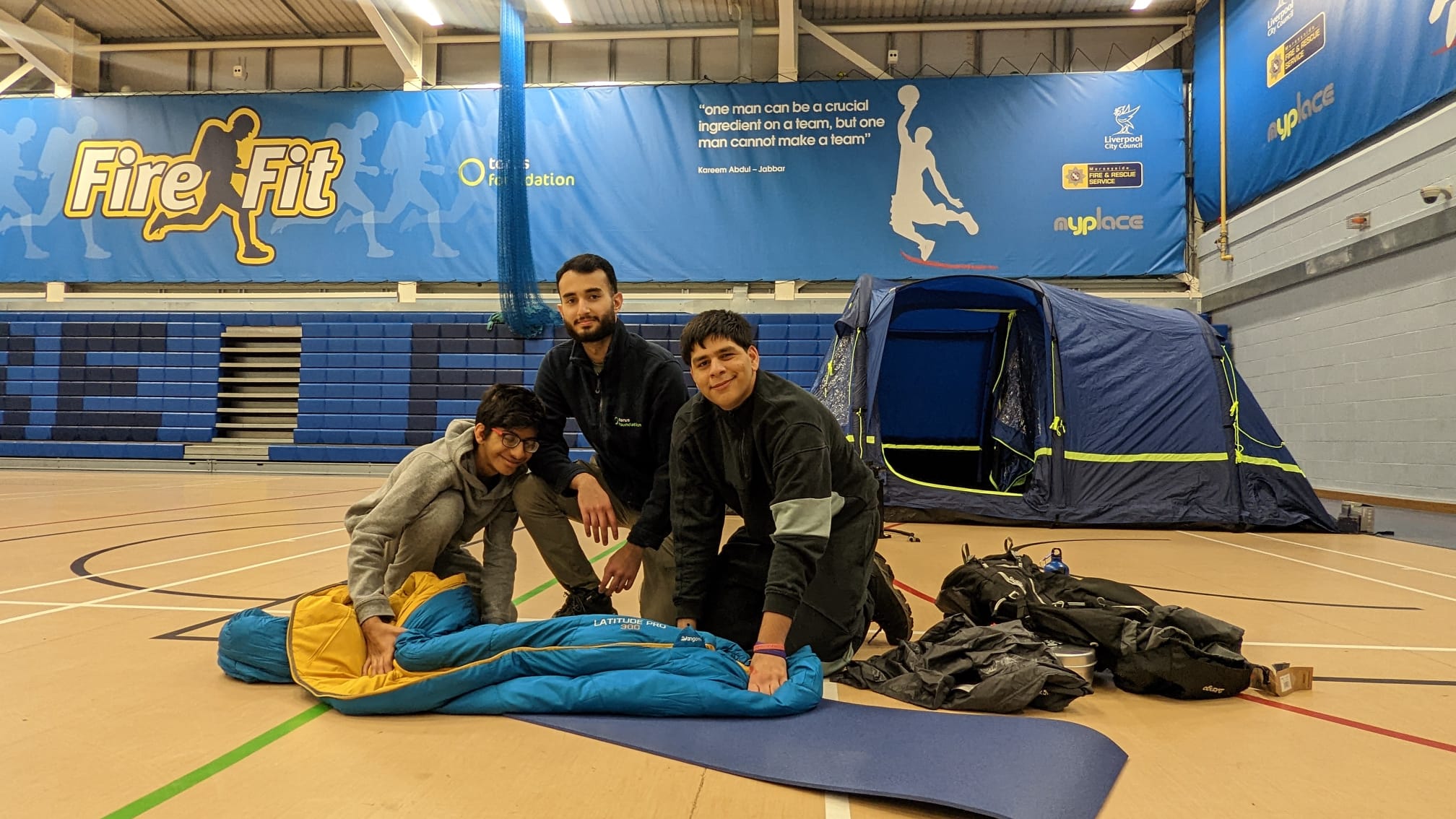 Photo of three people holding a sleeping bag